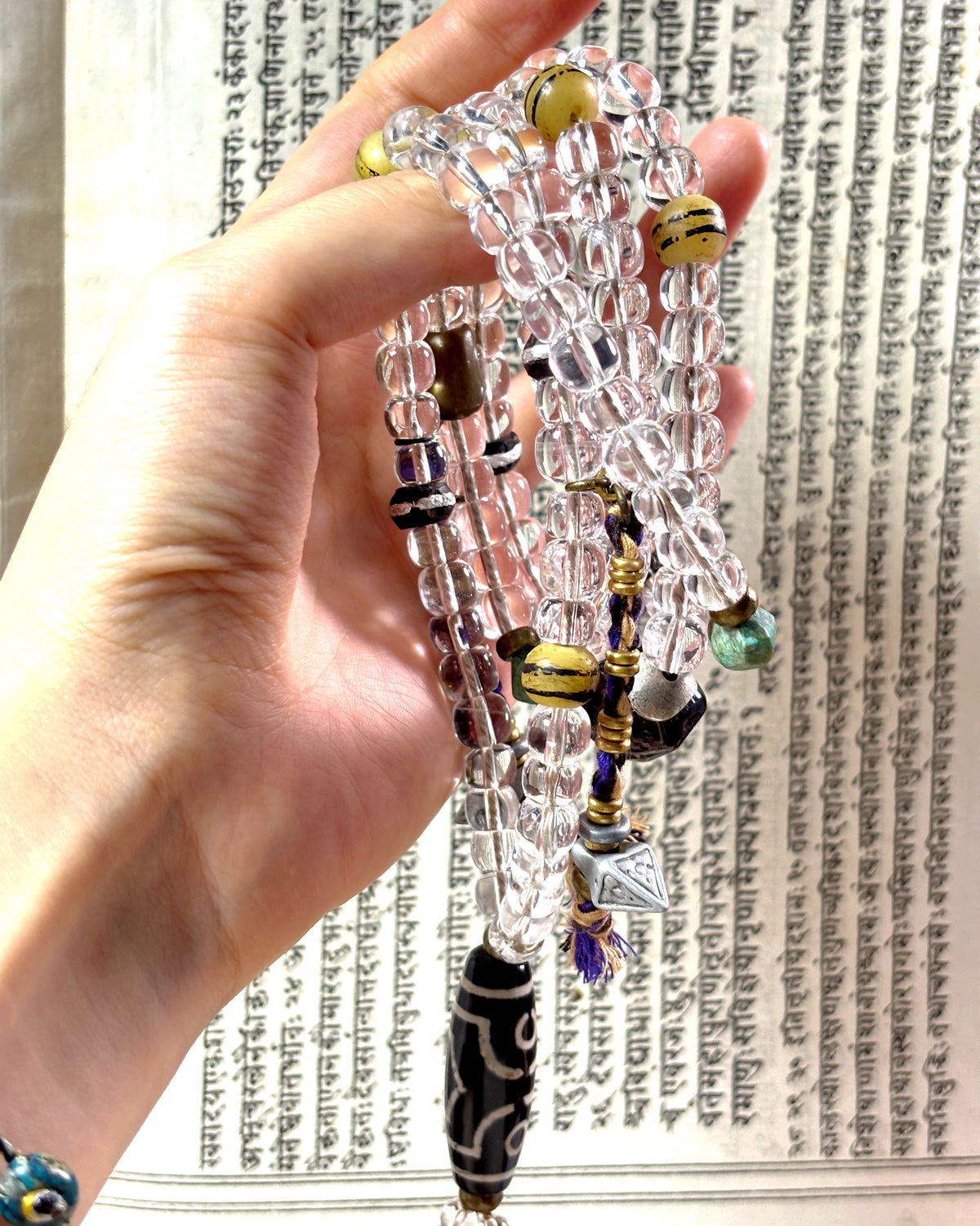 The Pilgrim #42 held in a hand, showing the long quartz loop, patterned guru bead and hanging counters