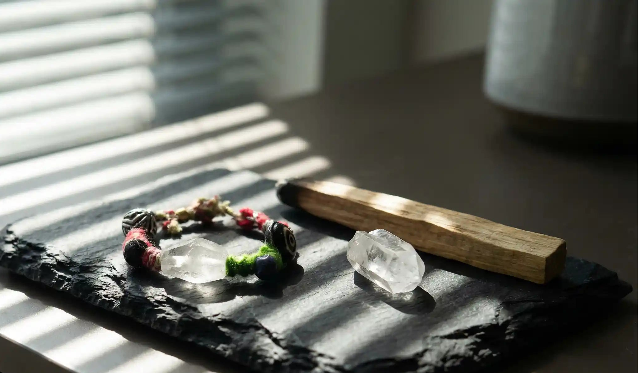 Decorative stone tray with a energy bracelet and a crystal and flowers on a wooden surface