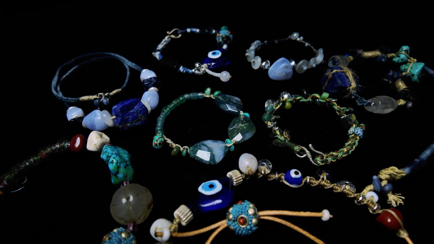 A collection of one-of-one gemstone talismans arranged on a dark surface